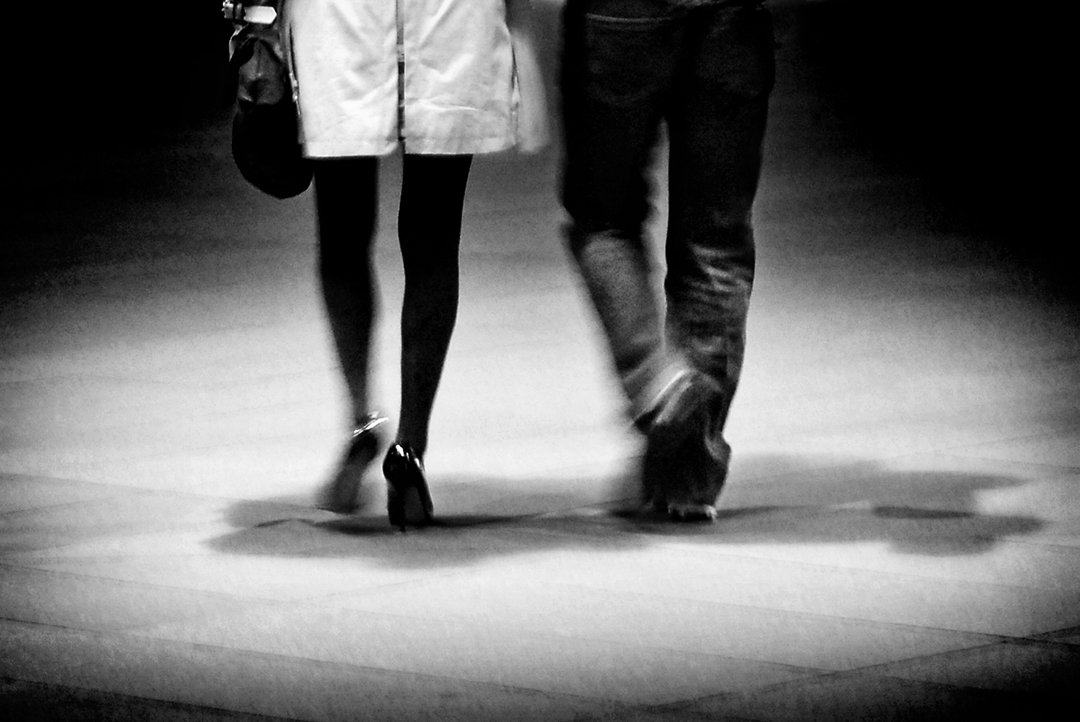 Two people walking together, seen from the waist down.